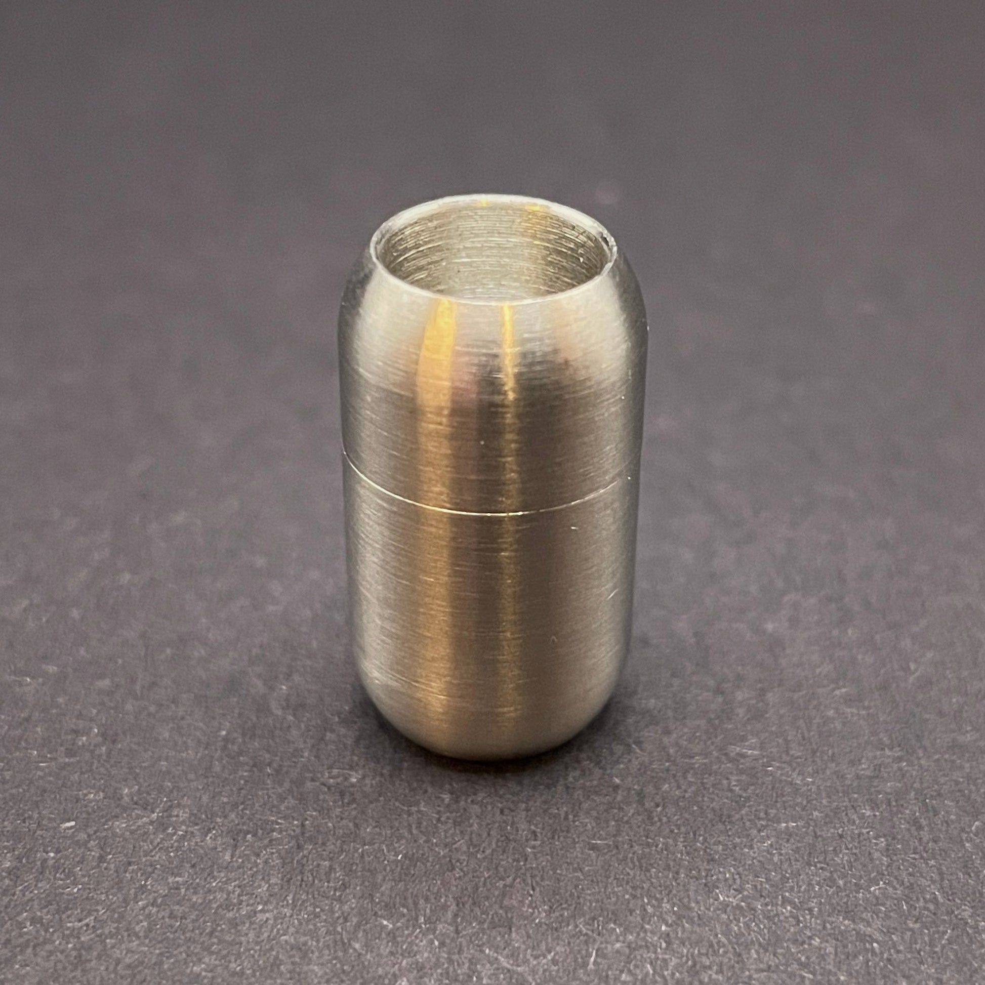 Stainless Steel cylindrical metal magnetic bracelet clasp, displayed on a dark textured background.