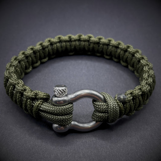 Flat lay of Army Green cobra knot paracord bracelet on a dark grey surface