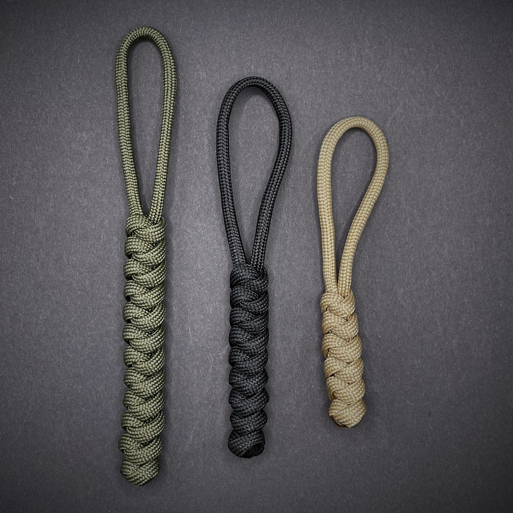 Flat lay of a 3 550 Paracord knife lanyards on a dark grey background