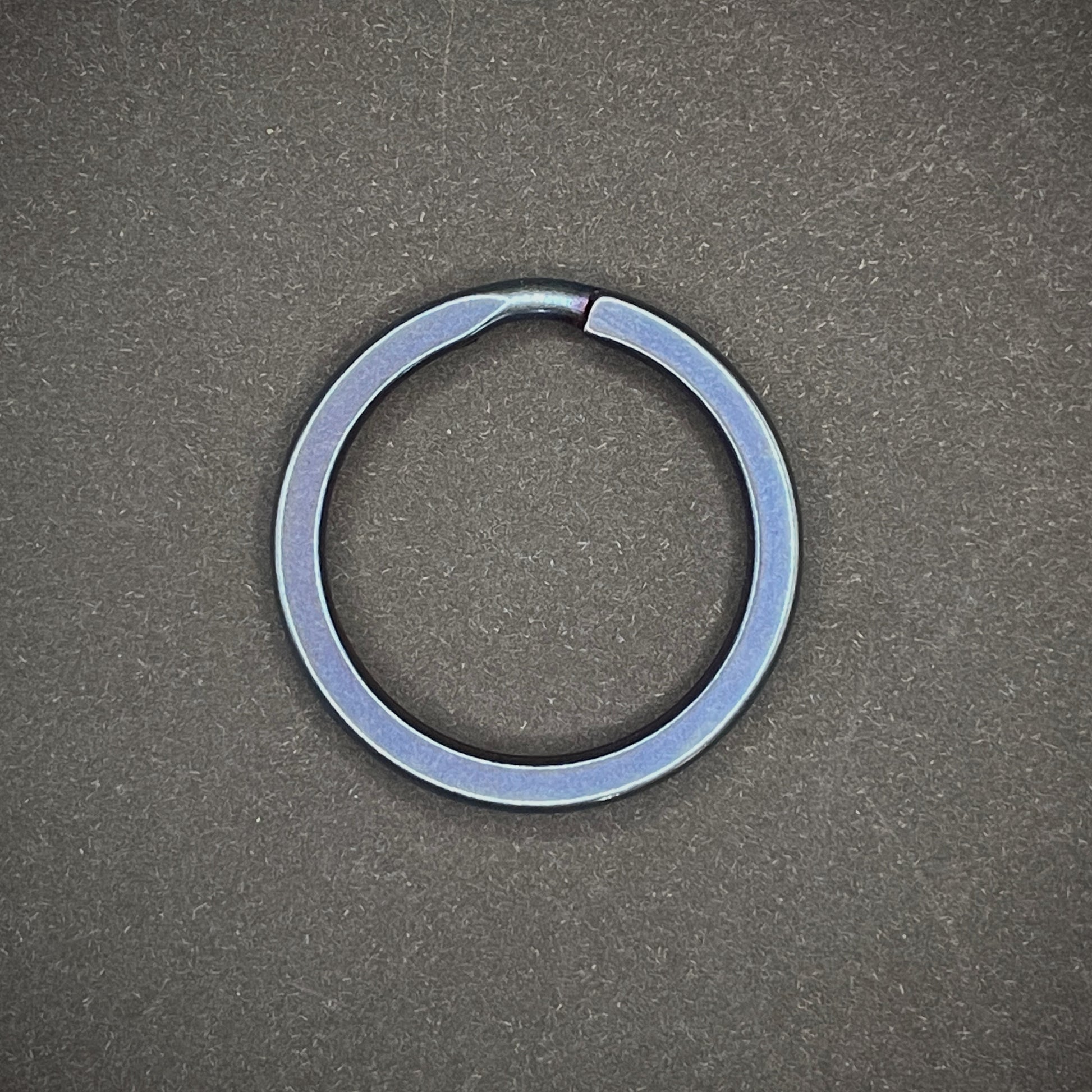 A Blue Titanium Split Ring on a dark grey background