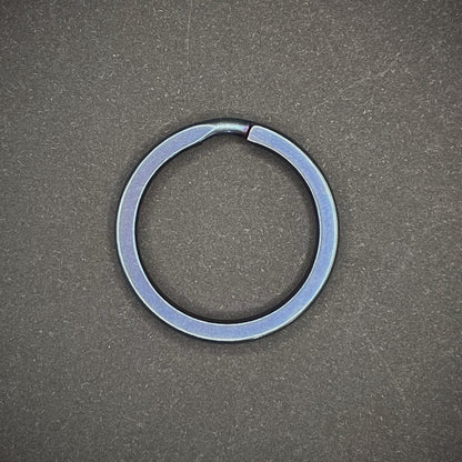 A Blue Titanium Split Ring on a dark grey background