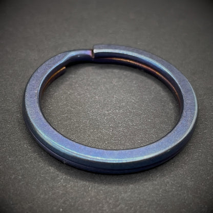 A Blue Titanium Split Ring on a dark grey background