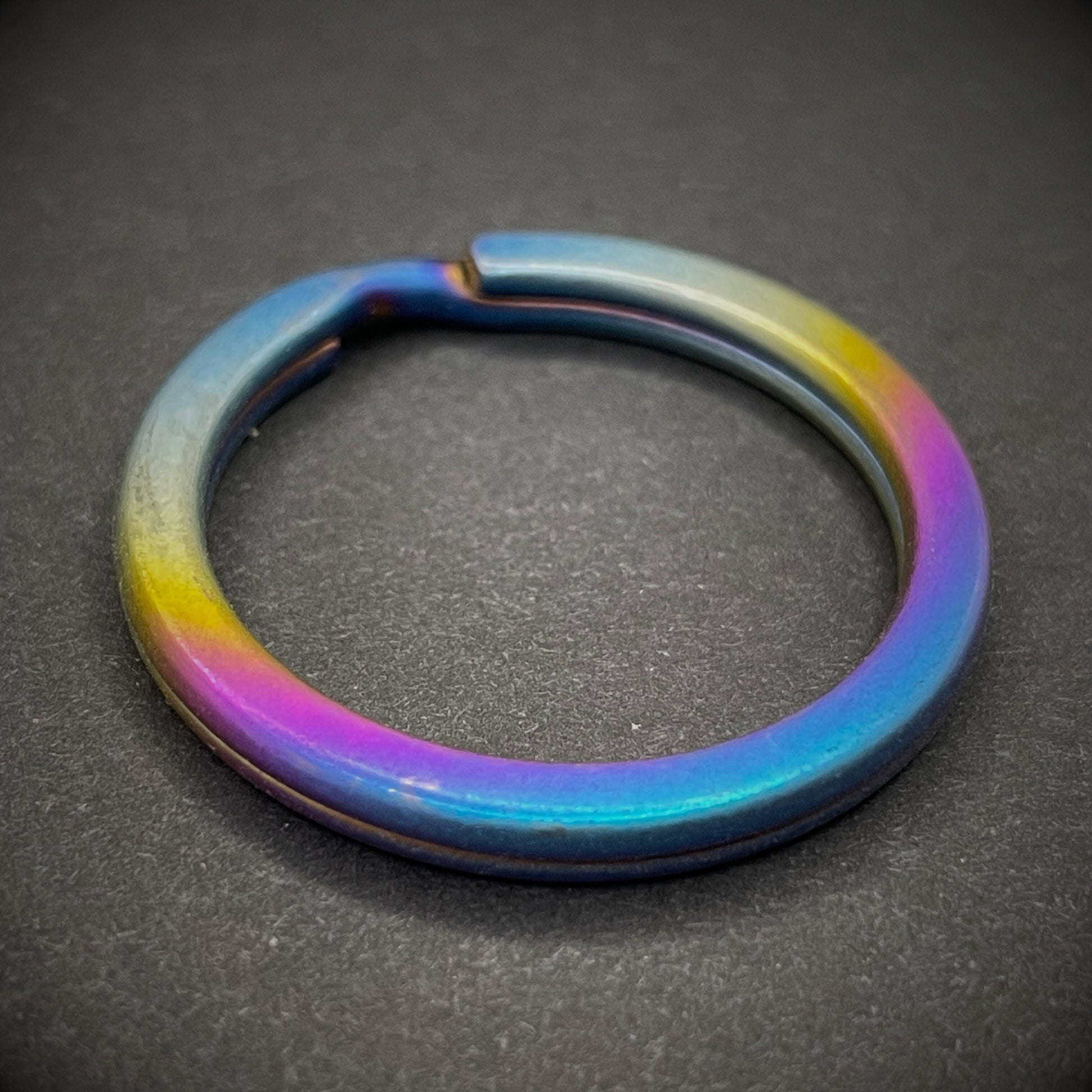 A Sunset Titanium Split Ring on a dark grey background