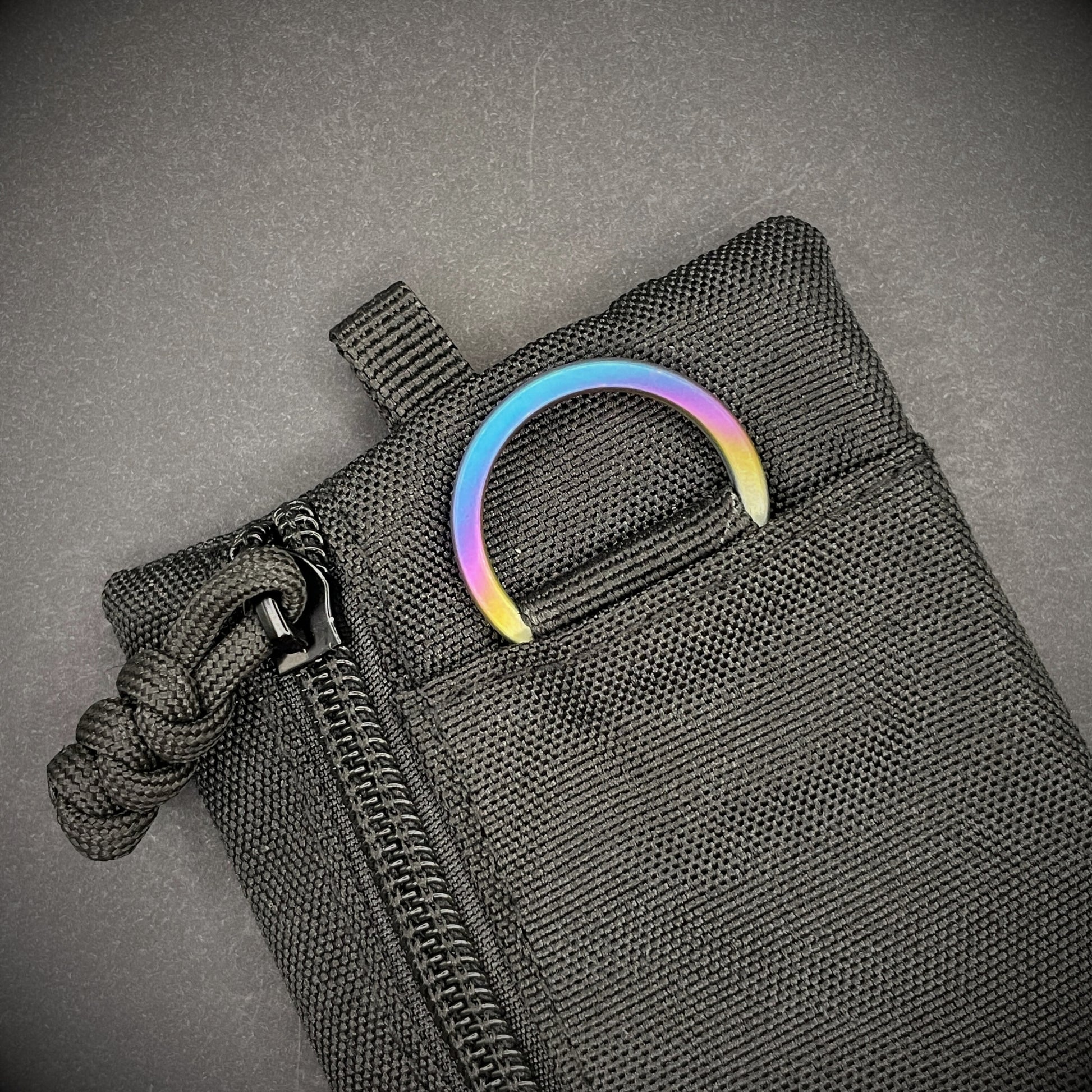 An Sunset Titanium Split Ring on a black pouch laid on a dark grey background