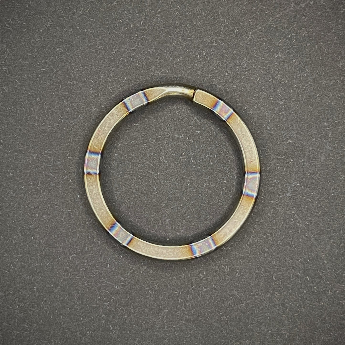 A Zebra Titanium Split Ring on a dark grey background