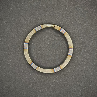 A Zebra Titanium Split Ring on a dark grey background