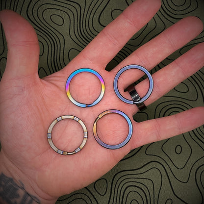 A group of Titanium Split Rings in the palm of an open hand above a topographical background