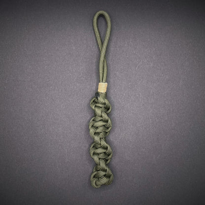 Flat lay of an Army Green 550 Paracord knife lanyards on a dark grey background