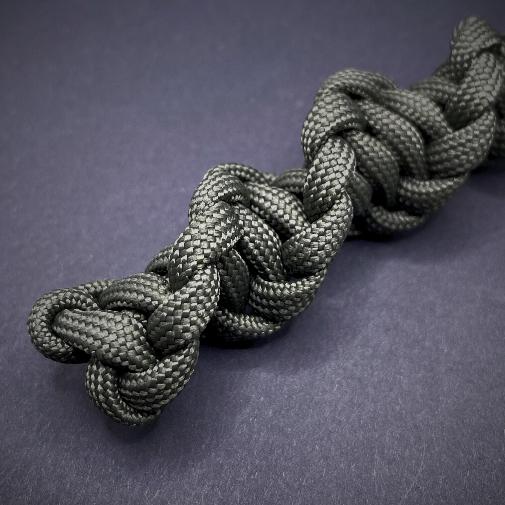 Flat lay of an Army Green 550 Paracord knife lanyards on a dark grey background