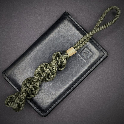 Flat lay of an Army Green 550 Paracord knife lanyards on a dark grey background