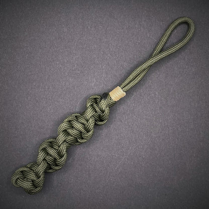Flat lay of an Army Green 550 Paracord knife lanyards on a dark grey background